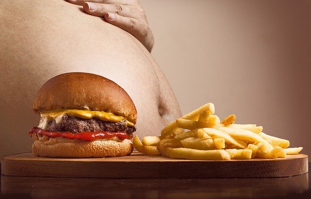 Hamburgery a hranolky neprospívají tělu – na obrázku je velké břicho, hranoly a hamburger