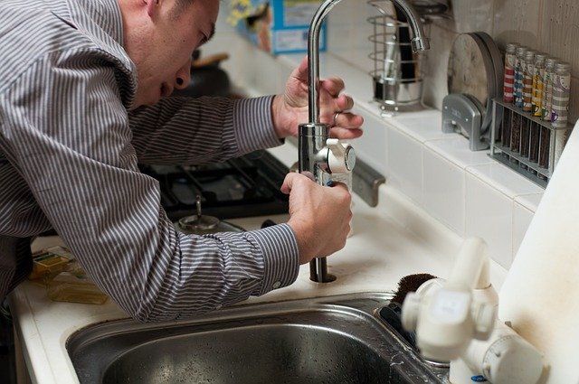 instalatér instaluje kuchyňskou vodovodní baterii